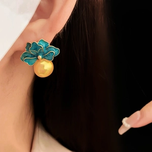 Close-up of vintage blue enamel flower earring with a yellow pearl drop on a model