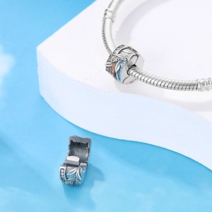 Macro shot of silver feather charm with blue enamel and colorful cubic zirconia inlay