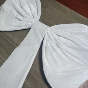 Detail of a large white velvet decorative bow with long ribbons on a wooden surface