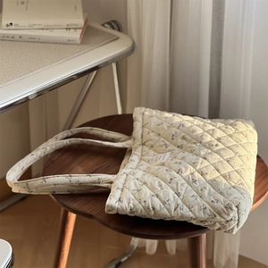 Gros plan détaillé d'un sac cabas fleuri en velours côtelé matelassé sur un tabouret