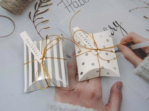 Detail of silver striped and polka dot pillow gift boxes with gold string and tags