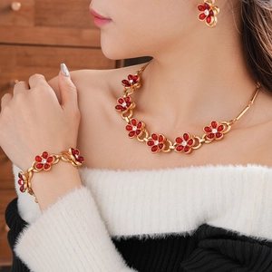 Detailed view of vintage gold necklace and bracelet set with red floral crystal motifs