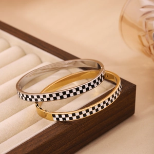 Minimalist gold and silver checkered enamel bangles displayed in a wooden jewelry box