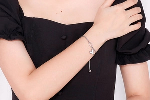 Close-up of heart charm stainless steel adjustable bracelet worn by a model