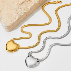 Minimalist gold and silver heart necklaces with snake chains displayed on natural stone
