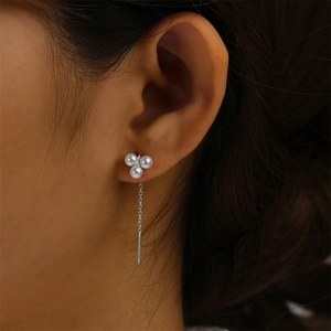 Macro shot of silver tassel earrings with three white pearls in a triangular setting
