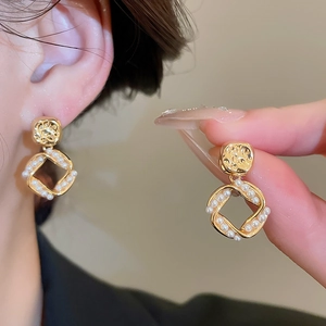 Detail of 18K gold-plated square pendant earrings with fine pearl inlay and hammered finish
