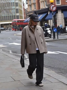 Street style shot of a beige double-breasted wool jacket with black wide-leg trousers