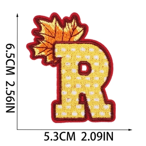 Detail of letter R embroidery patch with autumn maple leaf and polka dot pattern