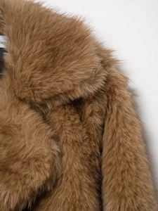 Close-up detail of soft faux fur texture and wide lapel collar on camel winter coat