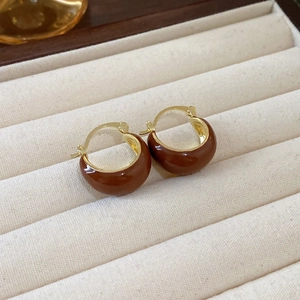 Brown enamel and gold hoop earrings displayed on cream velvet jewelry tray