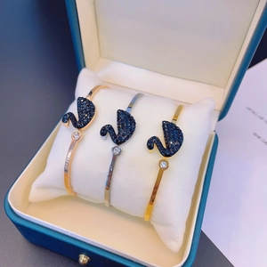 Three rose gold, silver, and gold open bangles with black swan and zircon in a blue gift box