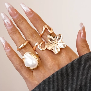 Detaillierte Nahaufnahme goldener Ringe mit Blumenmotiven und unregelmäßigen Perlen