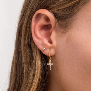 Detailed close-up of a gold cross hoop earring and small stud on a female model