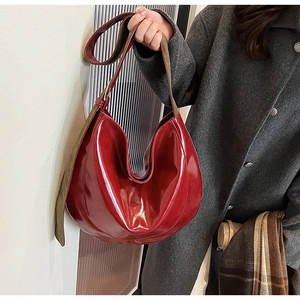 Detail of red patent leather Hobo bag with army green wide strap on grey coat