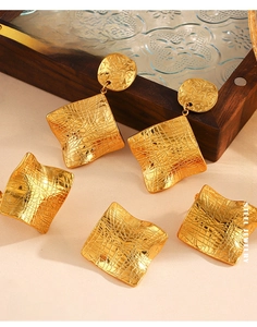 Detail of gold plated stainless steel square earrings with irregular grid texture