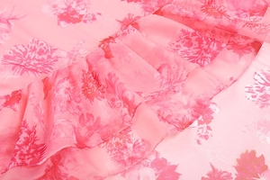 Detail of pink floral chiffon fabric with delicate ruffled edges and soft texture