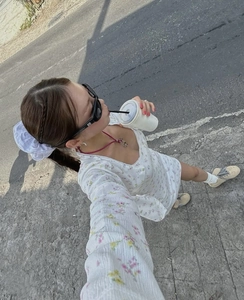 Détail de la robe tricotée à fleurs blanches avec dentelle au col et nœuds roses soyeux