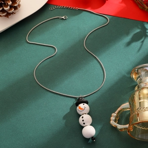 Gros plan détaillé d'un collier pendentif bonhomme de neige sur fond de fête rouge et vert