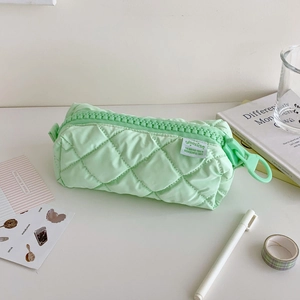 Close-up of mint green quilted pencil case with oversized plastic zipper and woven label