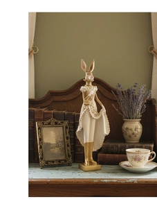 Detail of vintage resin rabbit figurine in Victorian gold dress on a classic bookshelf
