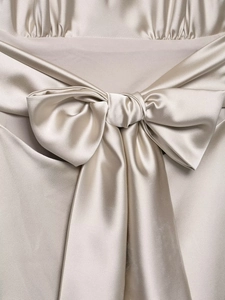 Detail of silk satin champagne gold dress featuring a delicate bow and fabric texture