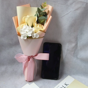Detail of small artificial rose bouquet with yellow flowers and pink ribbon wrap