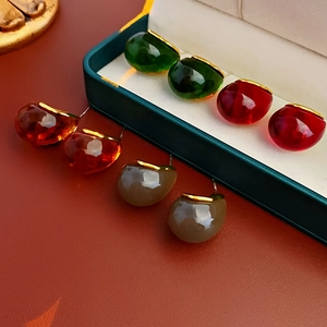 Detail view of colorful resin teardrop earrings with gold accents in a green jewelry box