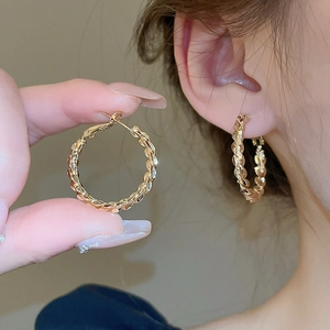 Gold twisted hoop earrings featuring high-gloss texture and elegant geometric round design