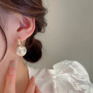 Gros plan sur boucles d'oreilles perles blanches avec zircons dorés sur un mannequin