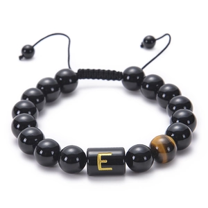 Detail of adjustable obsidian bracelet with tiger eye stone and golden letter E bead