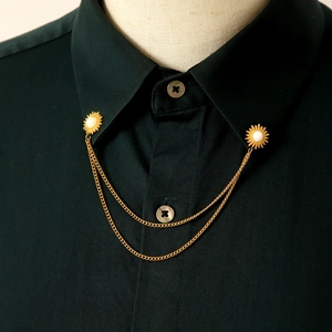 Dettaglio di spille da colletto a sole dorate vintage con doppie catene su camicia