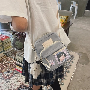 Gros plan sur un sac bandoulière gris clair en toile avec poche transparente et sangle