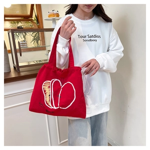 Detail shot of a red nylon tote bag with white apple print shown in a bright cafe setting