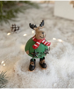 Close-up of cute iron reindeer ornament in green festive outfit on snowy surface