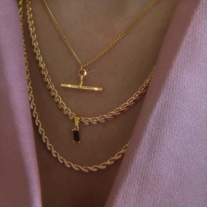 Detailed layered set of three gold necklaces featuring T-bar and black gemstone pendants
