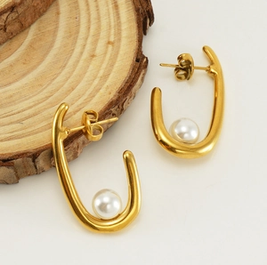 Gros plan de boucles d'oreilles géométriques en acier doré 18 carats avec perles blanches