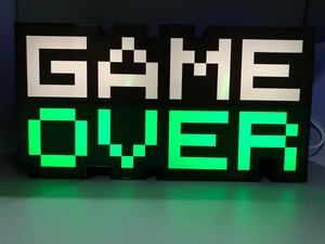 Macro shot of Game Over LED lamp showing glowing green pixel blocks on a dark base