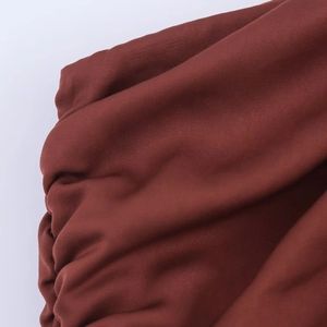 Gros plan sur la texture du tissu plissé marron foncé avec détails de plis fins
