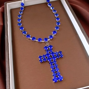 Detail of blue rhinestone cross pendant necklace with silver metal chain in jewelry box