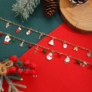 Gros plan de bracelets de Noël dorés avec breloques de Père Noël sur fond rouge et vert
