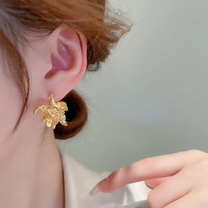 Detailed macro view of irregular gold petal earrings with metallic textured finish