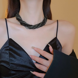 Dettaglio di una collana bohémien multistrato intrecciata con perline colorate su modella