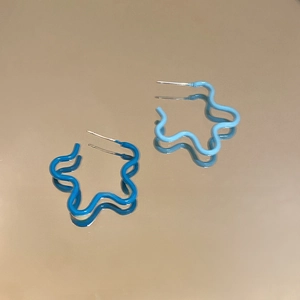 Détail de boucles d'oreilles vagues avec émail bleu foncé et bleu clair sur métal