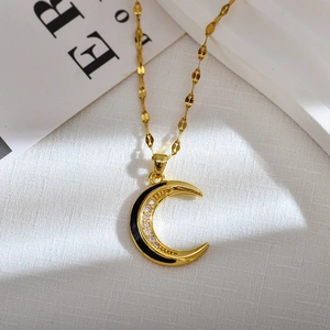 Macro shot of gold moon pendant featuring white zircons and black oil drip details