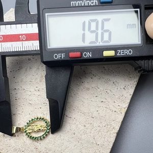 Detail showing 19.6mm diameter measurement of gold Jesus pendant with green stones