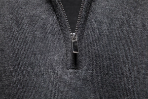 Gros plan sur la fermeture éclair en métal et la maille gris foncé texturée du pull pour homme