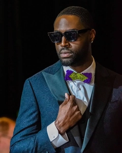 Close-up of Dwyane Wade wearing purple and yellow beaded bowtie with square sunglasses