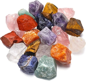 Assorted natural rough crystal stones including amethyst and tiger eye on white background