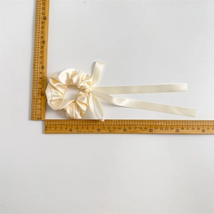 Cream satin bow scrunchie with long ribbons measured with a ruler for size